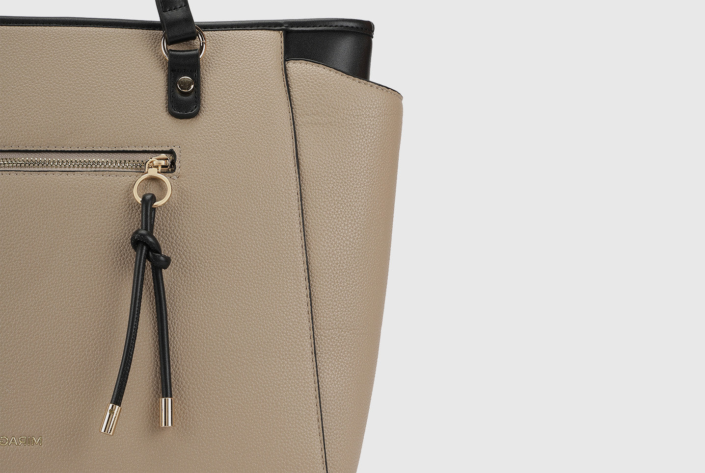 Close-up of beige Miraggio tote bag with black knotted zipper detail.