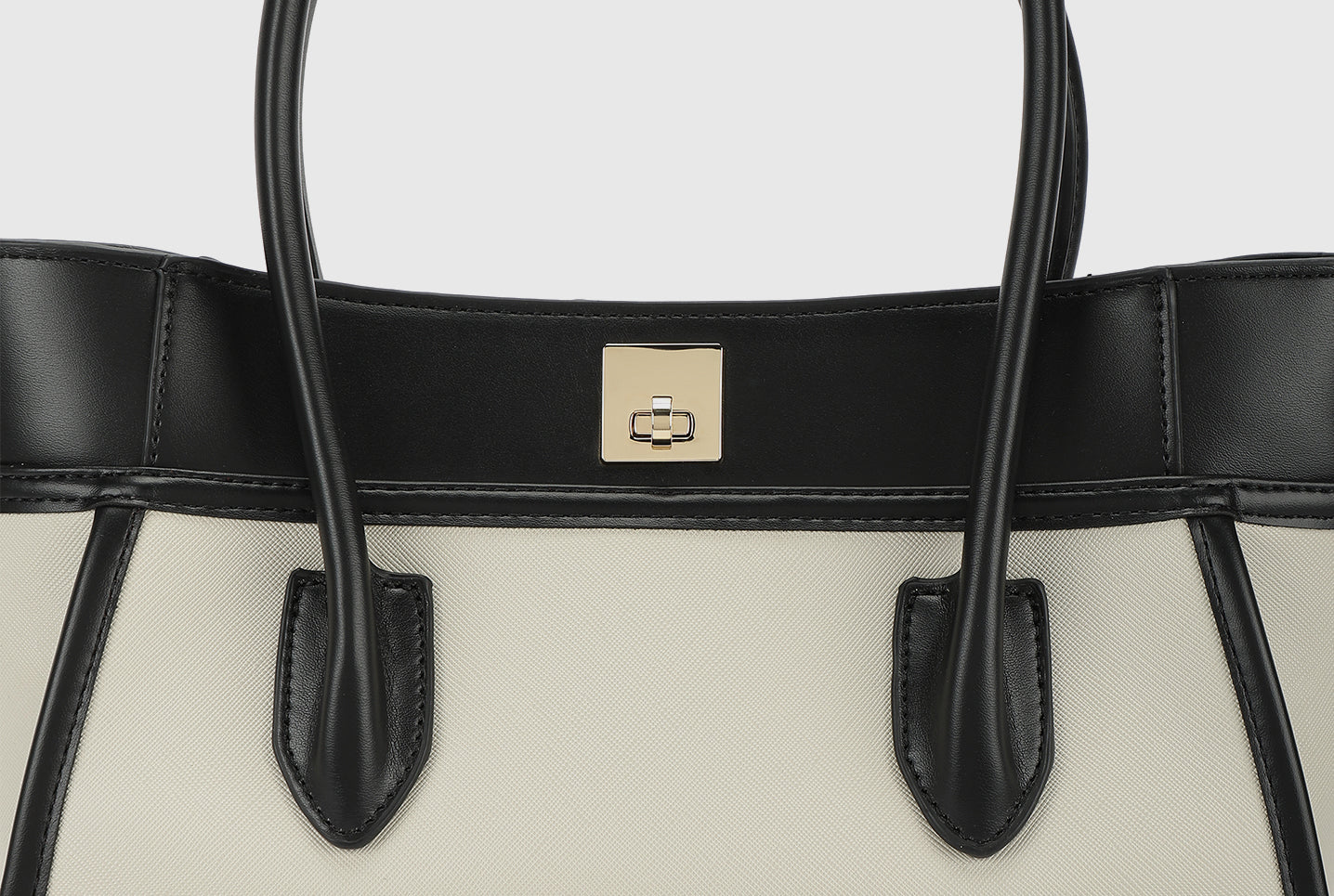 Top section of beige tote bag with black trim and gold square lock.