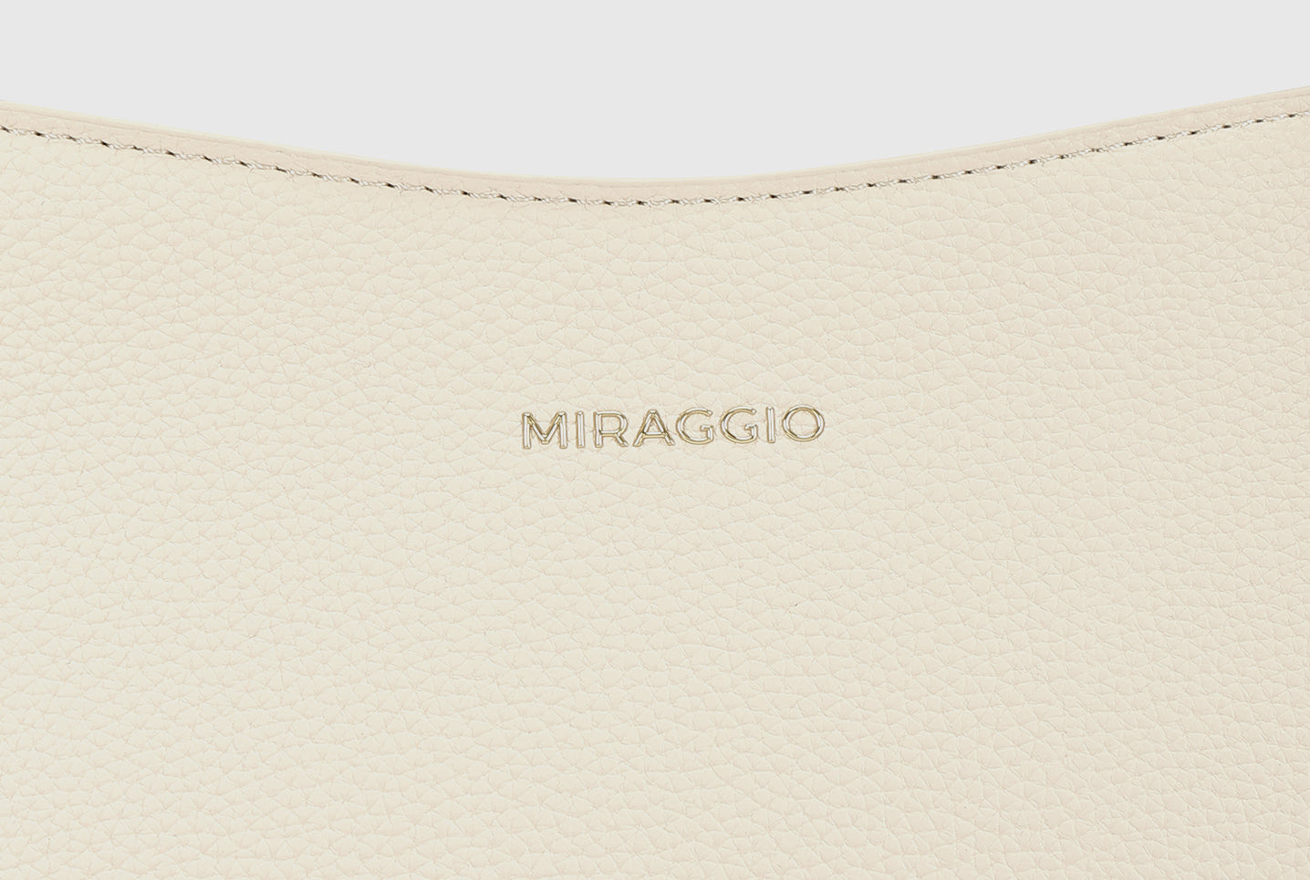 Close-up of Miraggio logo embossed on ivory textured leather bag.