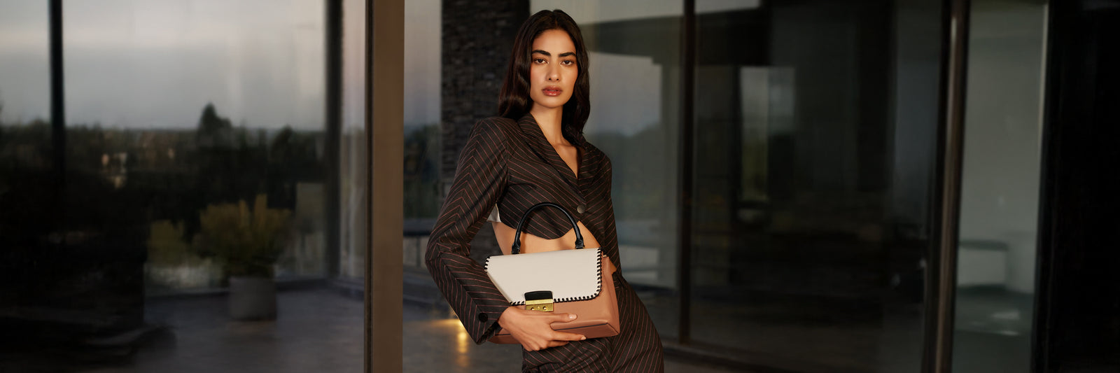 Woman  showing a beige color Miraggio handbag.
