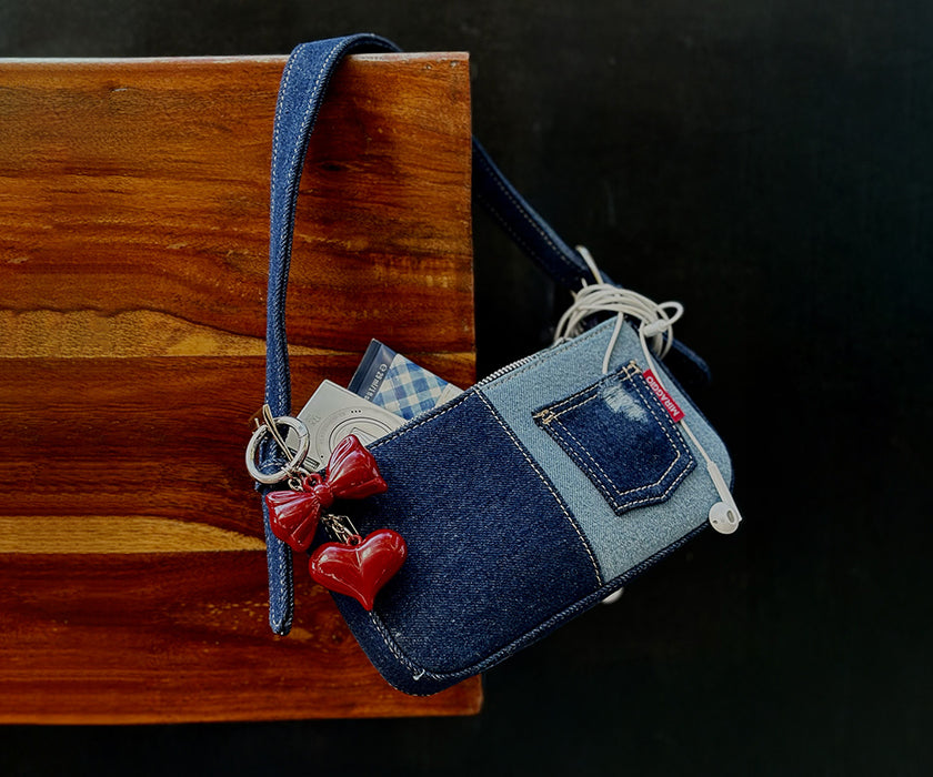 Miraggio charm bag made of denim material with red heart charms.
