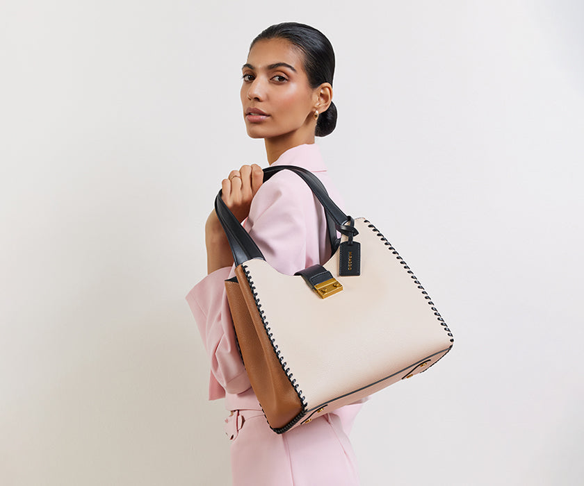 Woman standing with a Miraggio hobo bag.