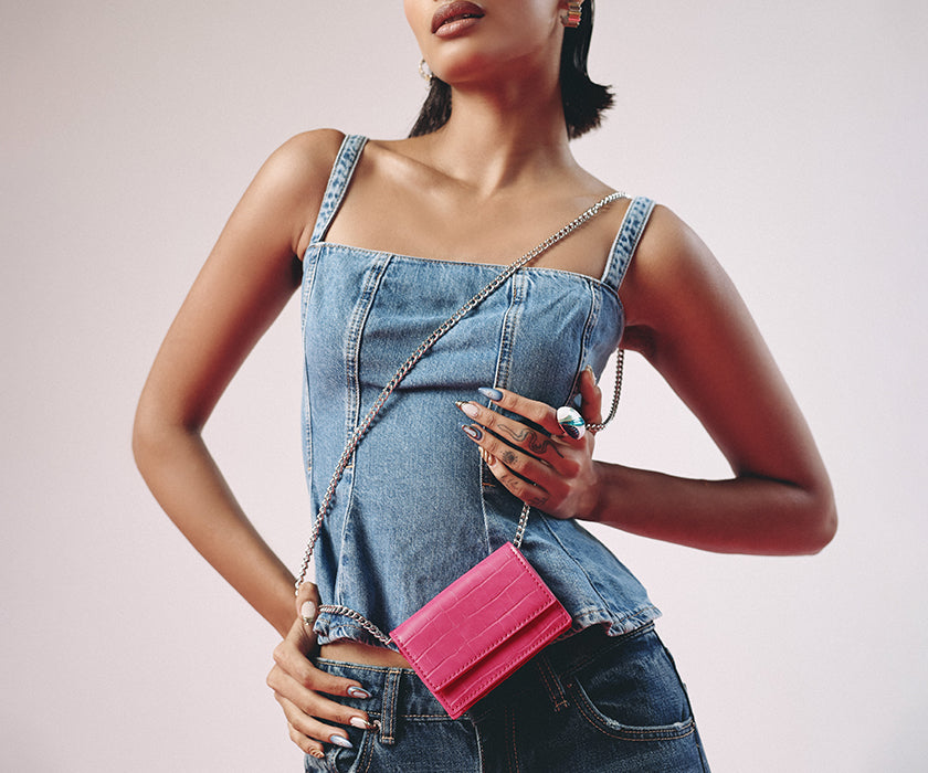 Woman wearing denim outfit with a pink wallet card holder from Miraggio.